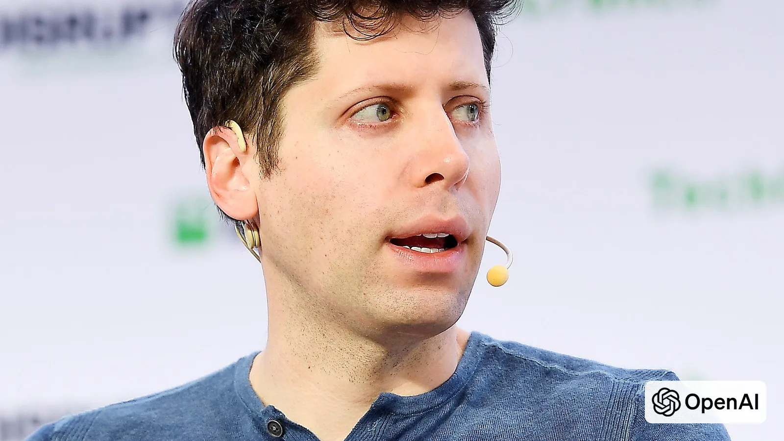 OpenAI CEO Sam Altman speaking at TechCrunch Disrupt, with the OpenAI logo